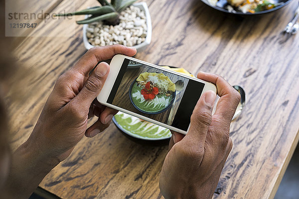 Männerhände fotografieren Smoothie-Schale mit Smartphone