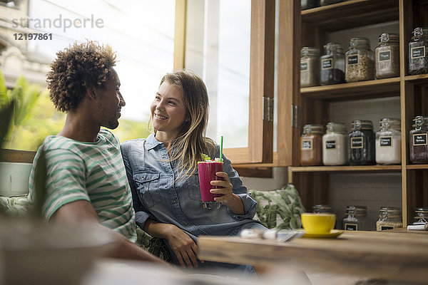 Lächelndes Paar im gemütlichen Café vor dem Fenster sitzend