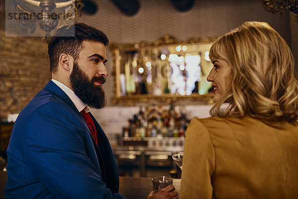 Elegantes Paar  das sich in einer Bar anlächelt.