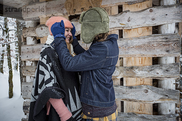 Glückliches Paar vor dem Holzhaufen im Freien im Winter