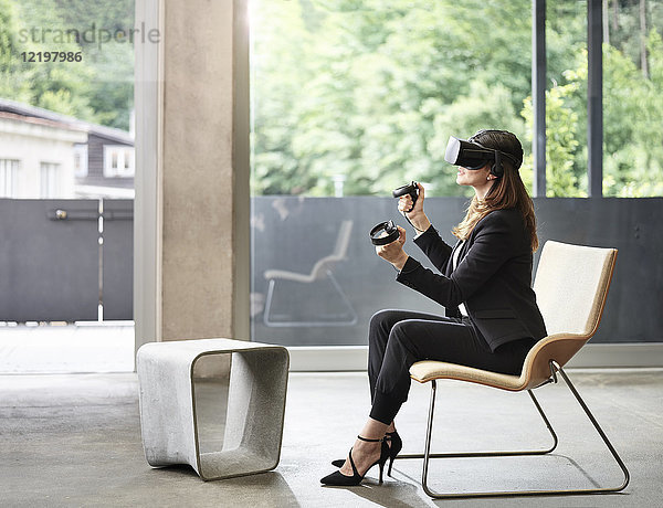 Geschäftsfrau mit VR-Brille auf Stuhl sitzend