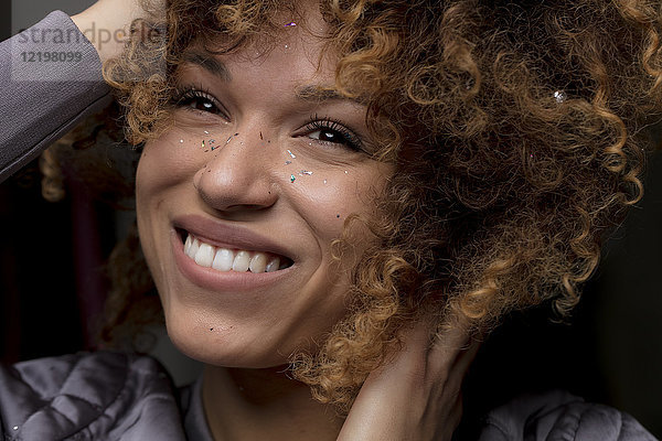 Porträt einer glücklichen Frau mit Konfetti im Gesicht