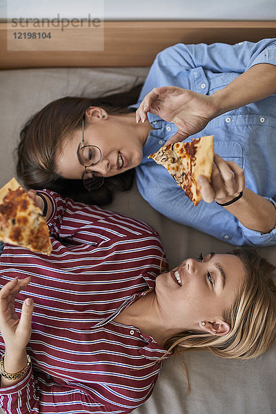 Zwei junge Frauen  die zusammen Pizza essen.