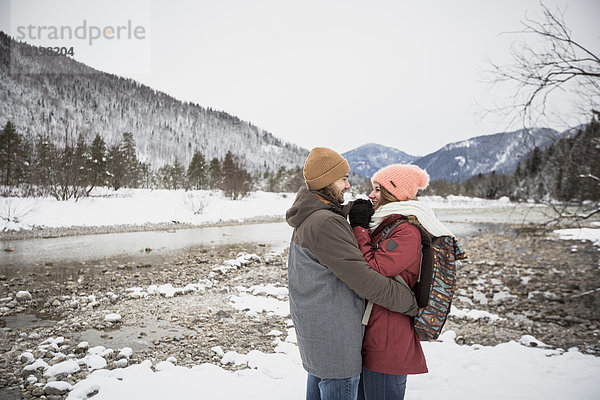Ein glückliches Paar  das sich im Winter auf einer Reise umarmt.