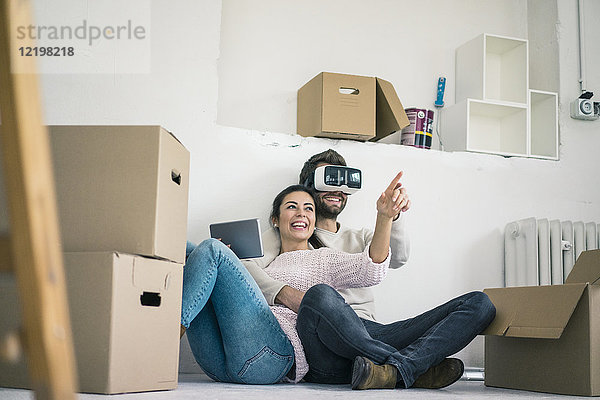 Paar sitzend im neuen Zuhause mit Mann mit VR-Brille