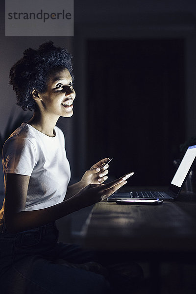 Junge Frau mit Kreditkarte  nachts von zu Hause aus online einkaufen