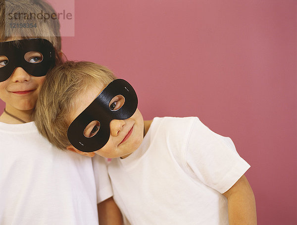 Porträt von zwei lächelnden kleinen Jungen mit schwarzen Augenmasken