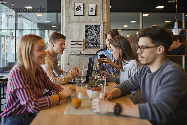 Gruppe von Freunden sitzen zusammen in einem Cafe mit Laptop  Smartphones und Getränken