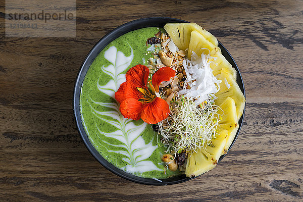 Dekorierte grüne Smoothie-Schale mit Ananas und essbarer Blume
