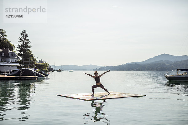 Frau beim Yoga auf dem Floß im See