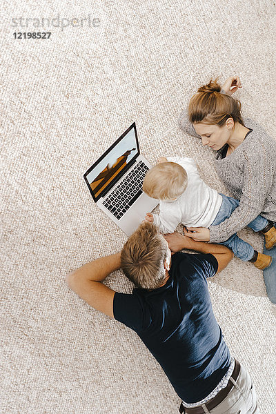 Familie mit Laptop auf dem Teppich