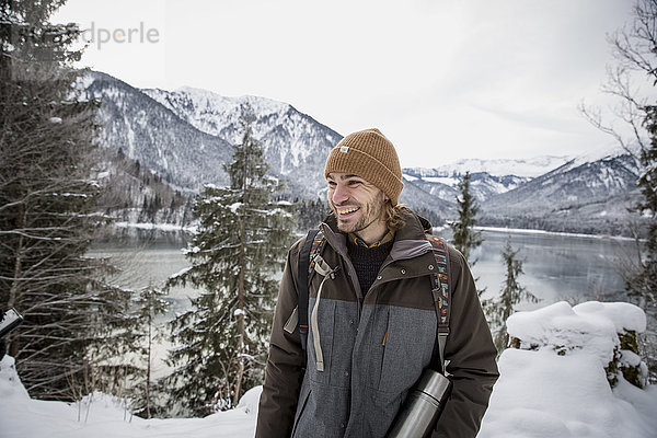 Glücklicher Mann in alpiner Winterlandschaft mit See