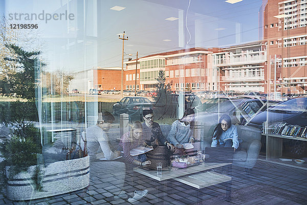 Gruppe von Freunden sitzen zusammen in einem Café mit Spiegelung der Glasscheibe