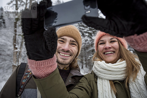 Ein glückliches Paar  das einen Selfie in der Winterlandschaft nimmt.