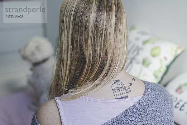Rückansicht der blonden Frau mit Tattoo am Hals