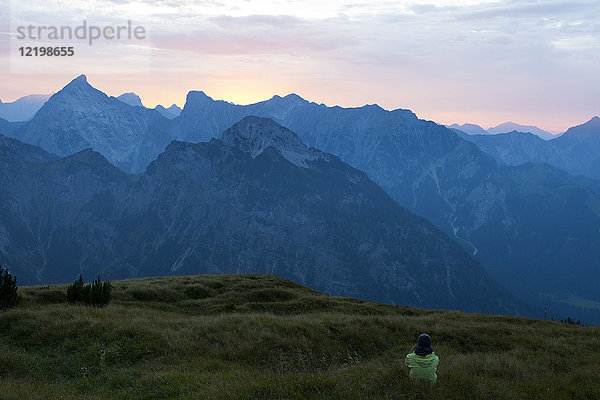 Österreich  Tirol  Wanderer in der Abenddämmerung auf der Alm