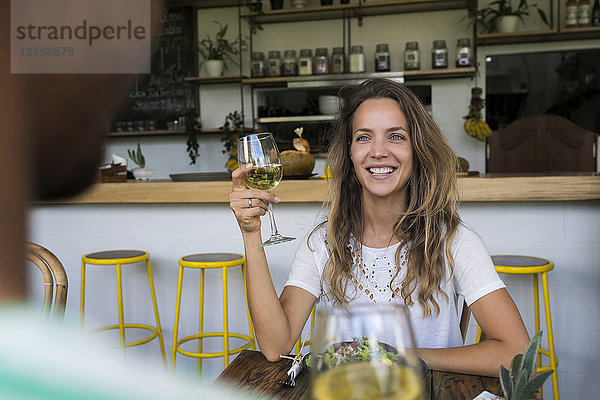 Lächelnde Frau mit einem Glas Wein  die den Mann in einem Café ansieht.