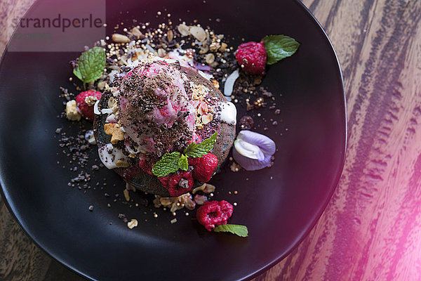 Dekoriertes rosa Dessert mit Himbeer- und Minzblättern