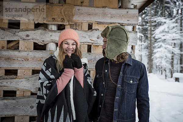 Porträt eines glücklichen Paares vor einem Holzhaufen im Freien im Winter