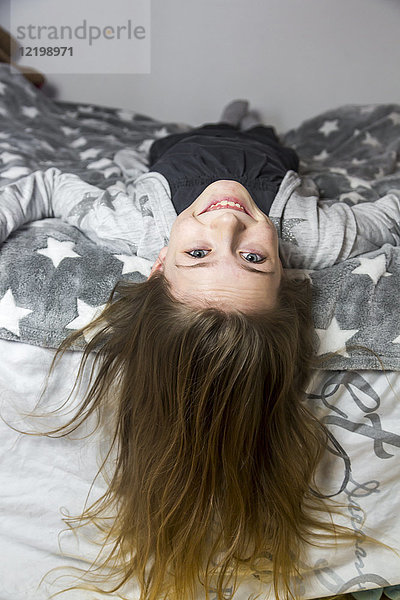 Porträt des lachenden Mädchens auf dem Bett liegend