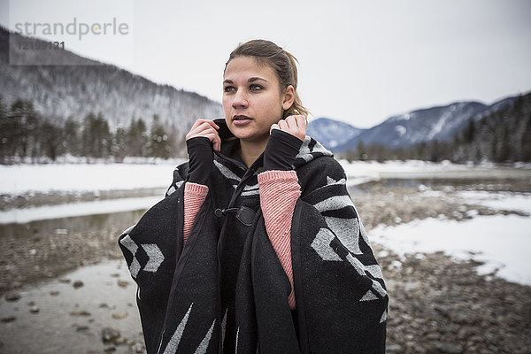 Junge Frau steht im Winter an einem Fluss