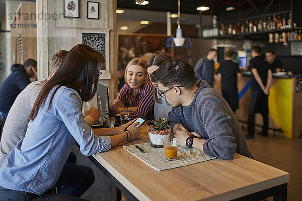 Gruppe von Freunden sitzen zusammen in einem Cafe mit Laptop  Smartphone und Getränken