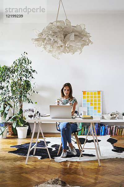 Junge Frau zu Hause mit Laptop auf dem Schreibtisch