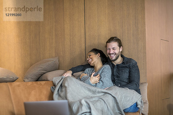 Lachendes junges Paar  das sich gemeinsam auf der Couch ausruht