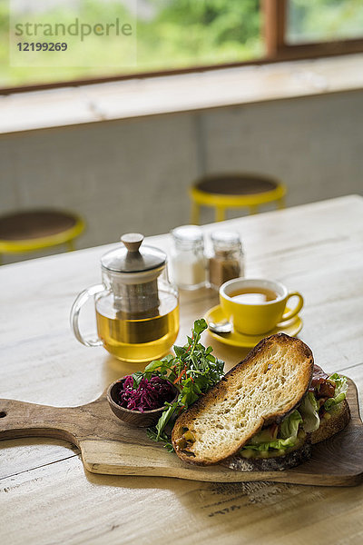 Krustenbrot mit grünem Salat und Rote Beete auf Holzteller und grünem Tee im Café