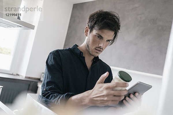 Portrait eines jungen Mannes  der eine Tablette benutzt  um Informationen über ein Produkt zu erhalten.