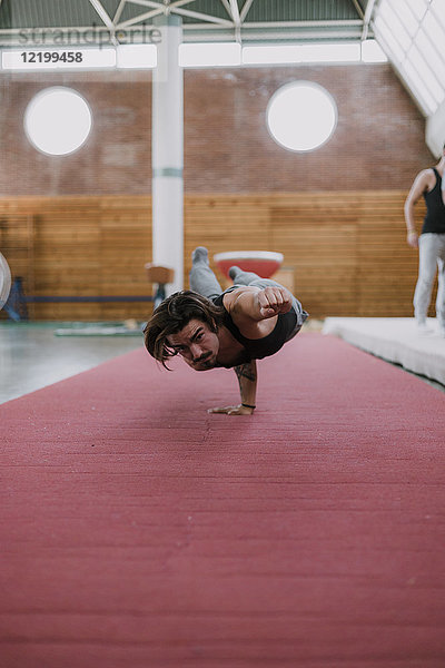 Junger Mann bei akrobatischen Übungen im Fitnessstudio