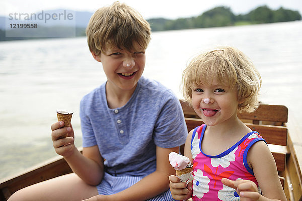 Porträt eines kleinen Mädchens  das im Ruderboot sitzt und mit seinem Bruder Eis isst.