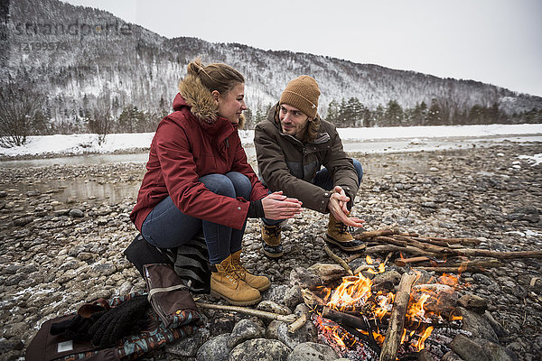 Paar auf einer Reise im Winter wärmende Hände am Lagerfeuer