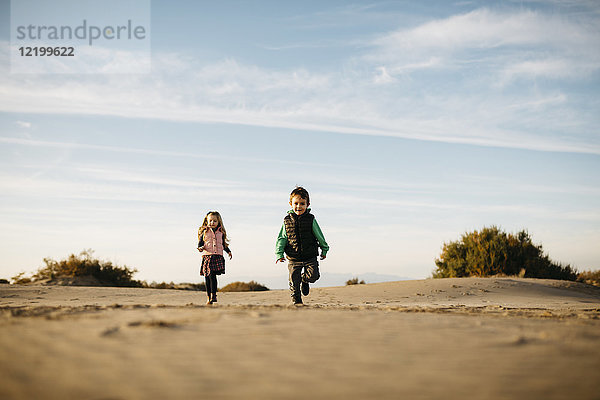 Zwei Kinder laufen im Winter am Strand.