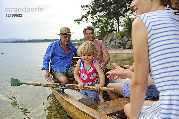 Deutschland  Bayern  Murnau  glückliches kleines Mädchen mit ihrer Familie im Ruderboot am Seeufer