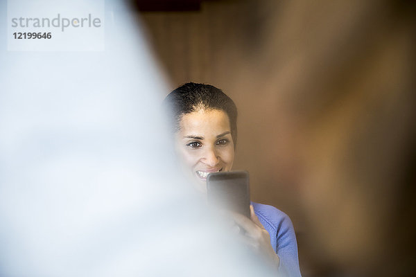 Porträt einer lachenden Frau beim Fotografieren mit dem Handy