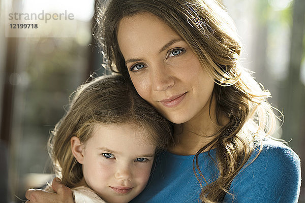 Porträt der lächelnden Mutter mit Tochter vor dem Fenster