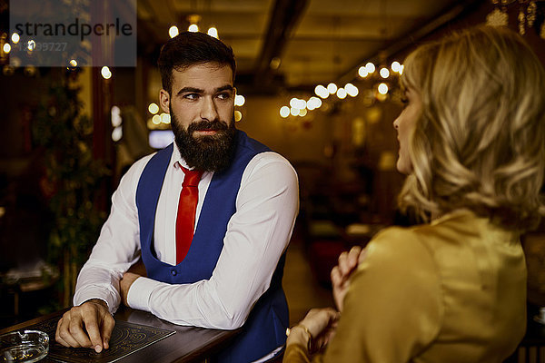 Modischer junger Mann  der eine Frau in einer Bar ansieht.