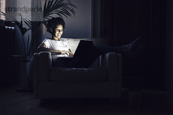 Junge Frau  die nachts online fernsieht  mit Laptop