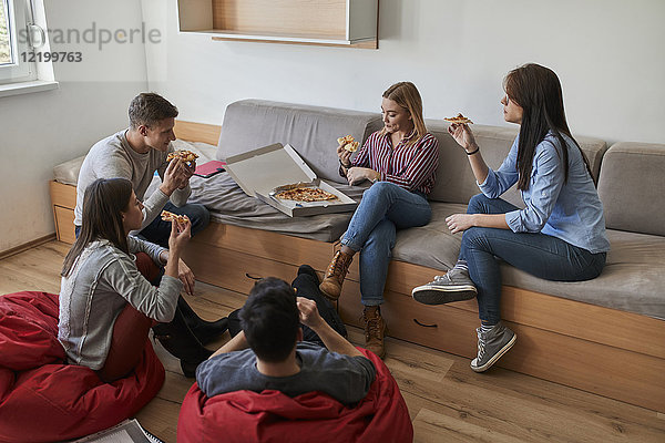 Gruppe von Schülern im Studentenwohnheim beim gemeinsamen Pizzaessen