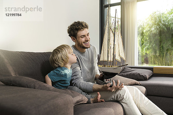 Vater und Sohn mit Spielzeugmodellschiff auf der Couch zu Hause