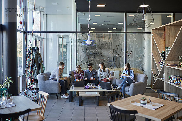 Gruppe von Freunden sitzen zusammen in einem Café mit Laptop