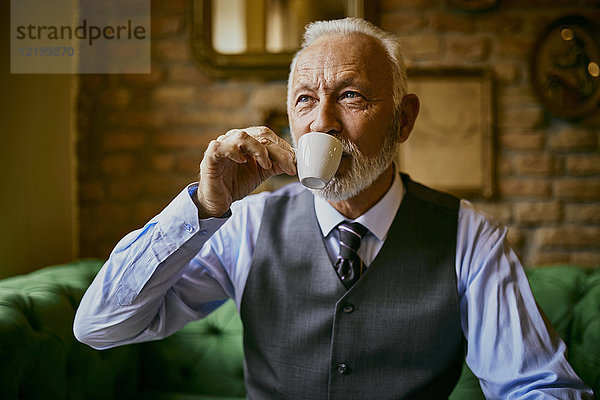 Eleganter älterer Mann beim Kaffeetrinken im Café