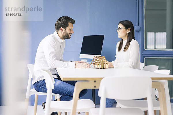 Mann und Frau im Gespräch mit Architekturmodell auf dem Tisch