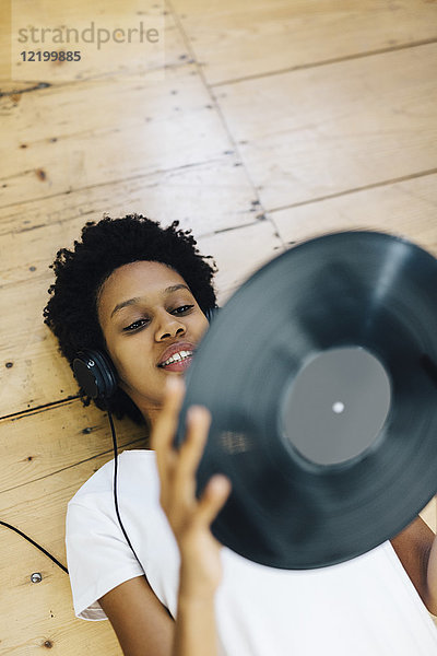 Junge Frau zu Hause beim Hören von Schallplatten  auf dem Boden liegend