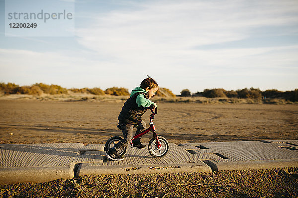 Junge läuft mit dem Fahrrad am Strand im Winter