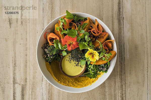 Dekorierter Salat mit Kürbis  Hummus  Brokkoli und essbarer Blume