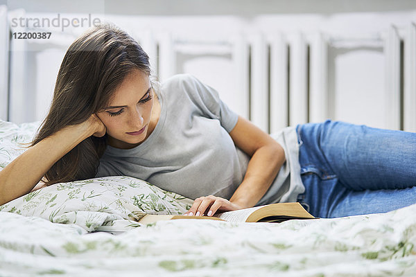 Junge Frau zu Hause im Bett liegend Lesebuch