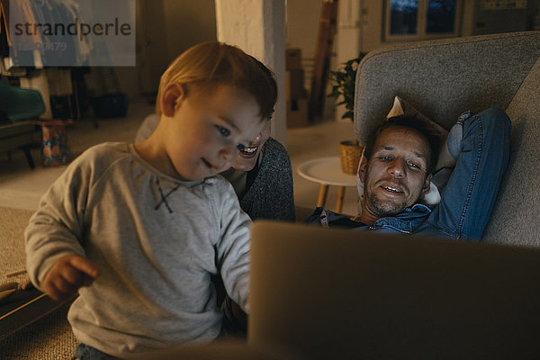 Familie betrachtet Laptop auf der Couch im Dunkeln