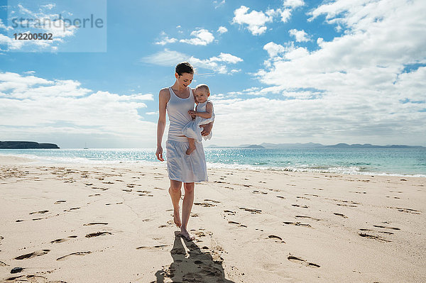 Mutter geht mit kleiner Tochter am Strand spazieren